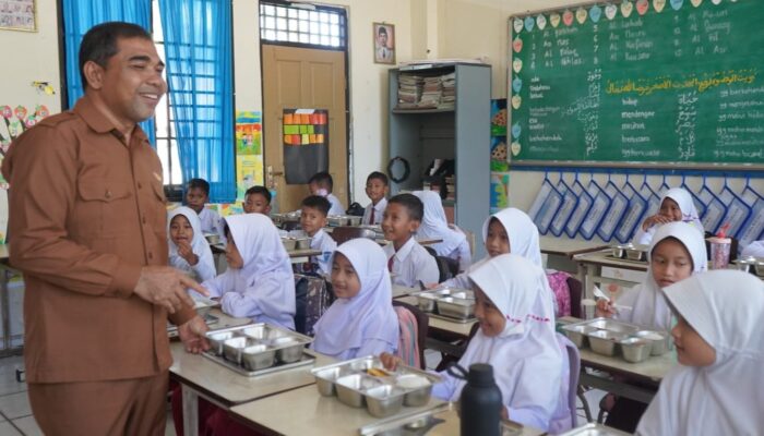 Foto : Pelaksana Tugas (Plt) Sekretaris Daerah Abdya, Amrizal, S.Sos., turun langsung meninjau pembagian makanan bergizi untuk 200 siswa di SD Negeri Tunas Bangsa, Senin (13/10/2025).
